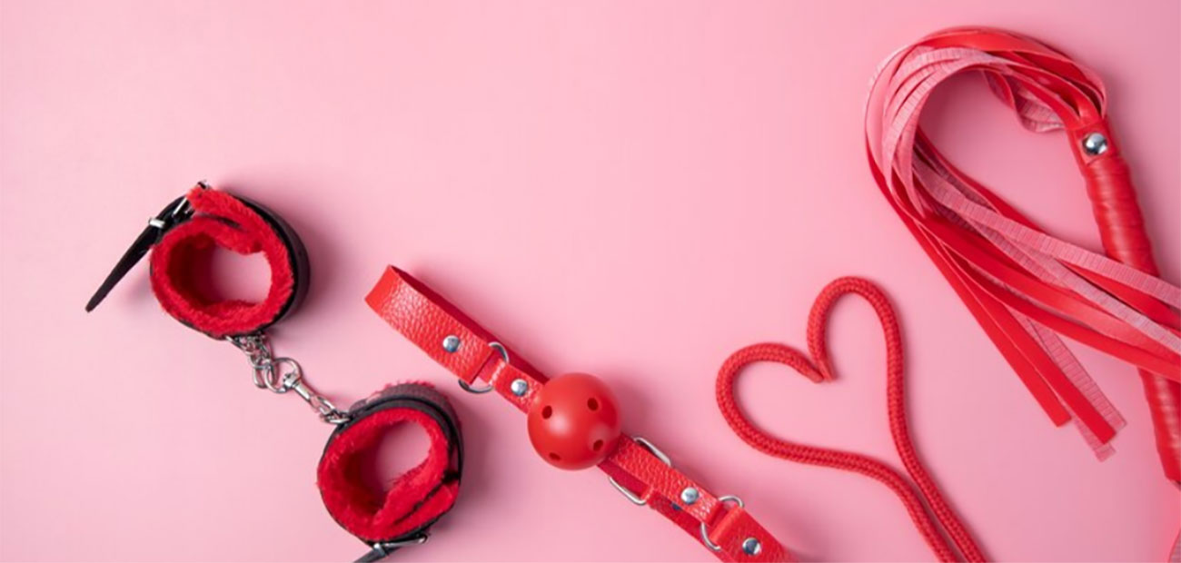 Accesorios BDSM rojos sobre un fondo rosa